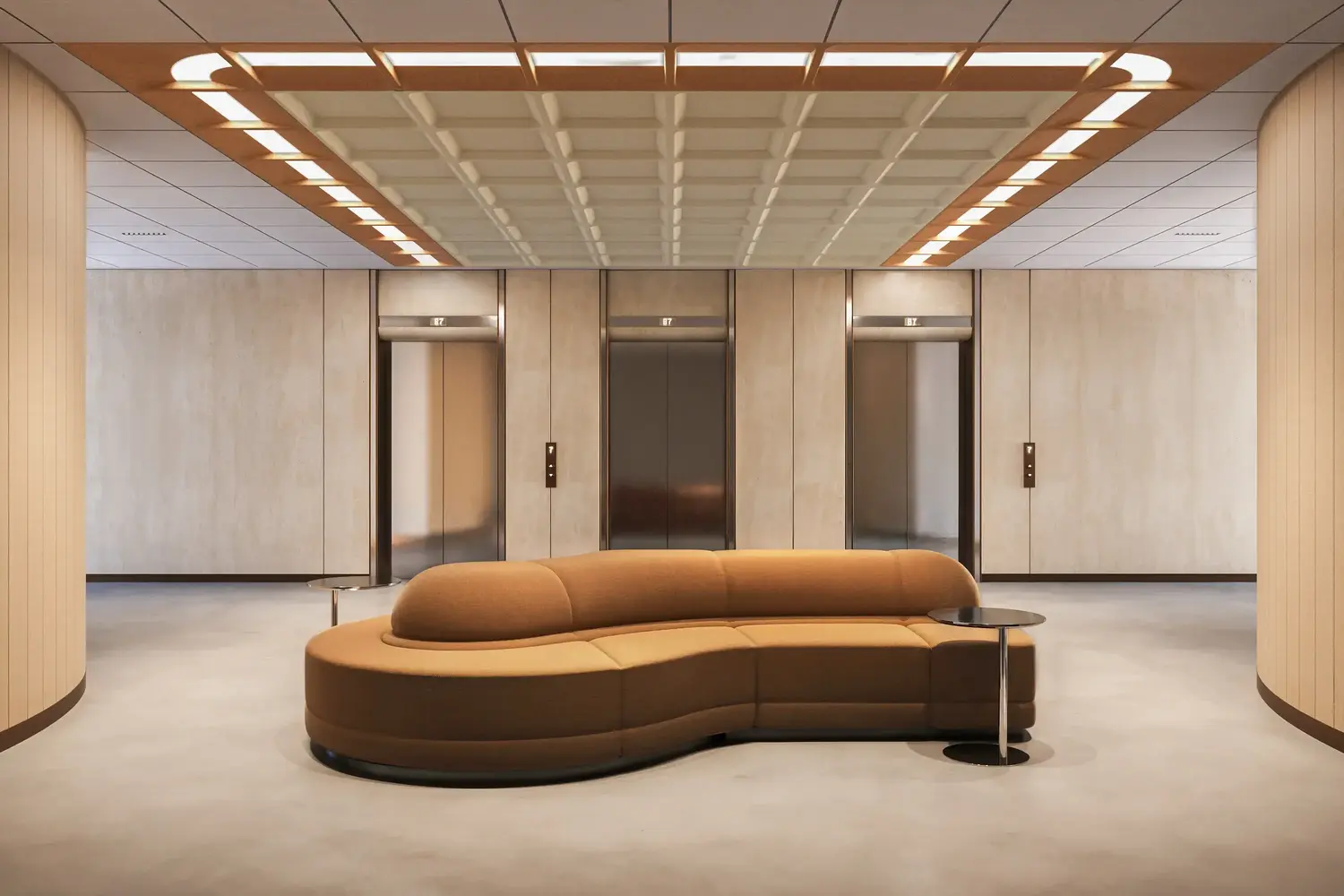 Tacet acoustic ceiling lighting in an elevator lobby with a curved tan sofa and stone-clad walls